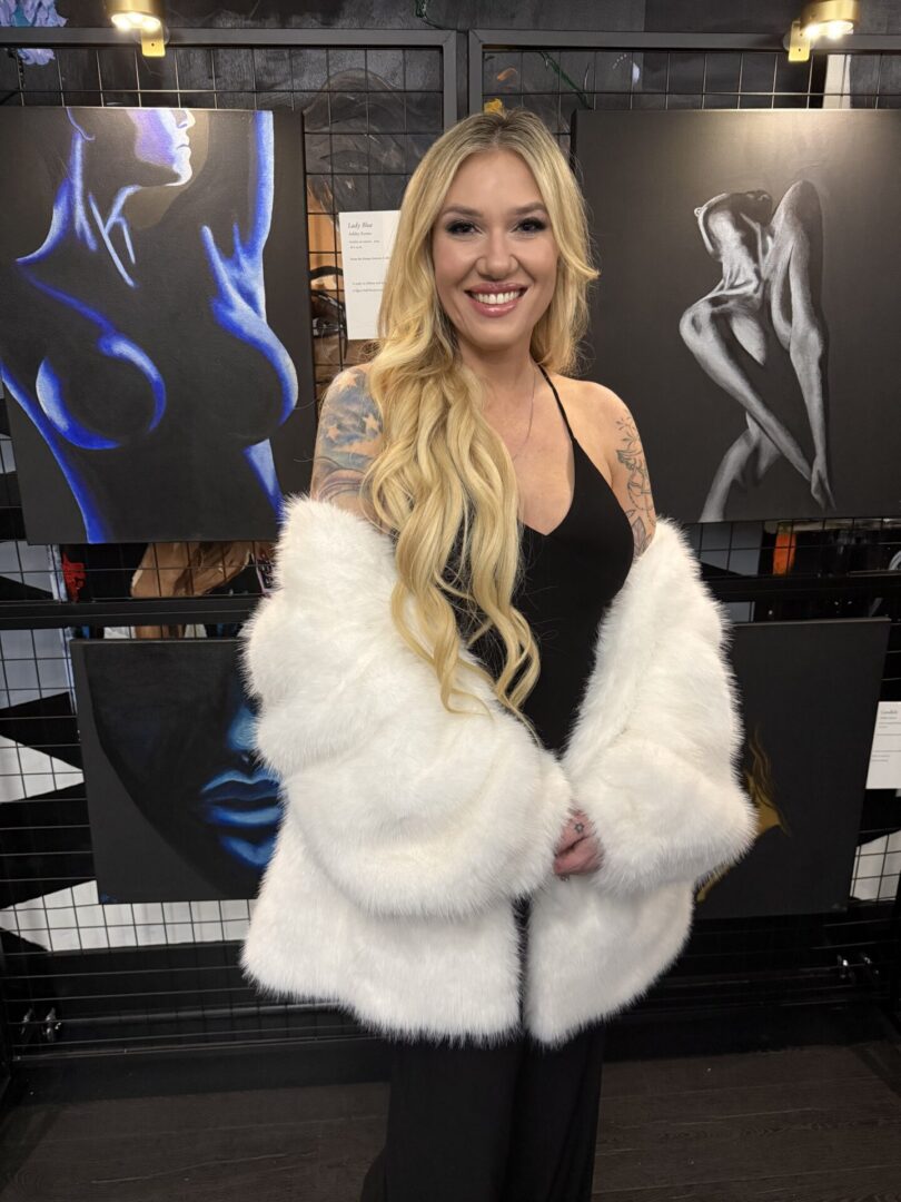 A woman with long blonde hair wearing a white fur coat and black dress.