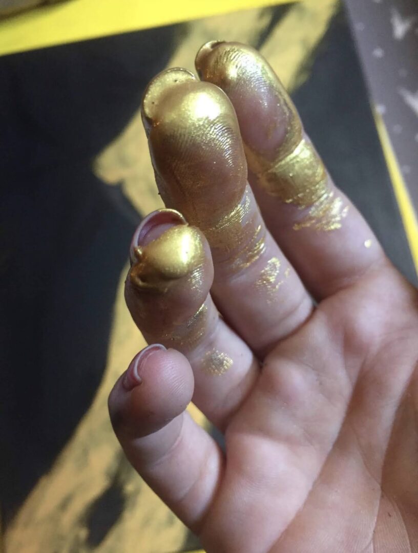 Fingers covered in gold paint with peeling skin.